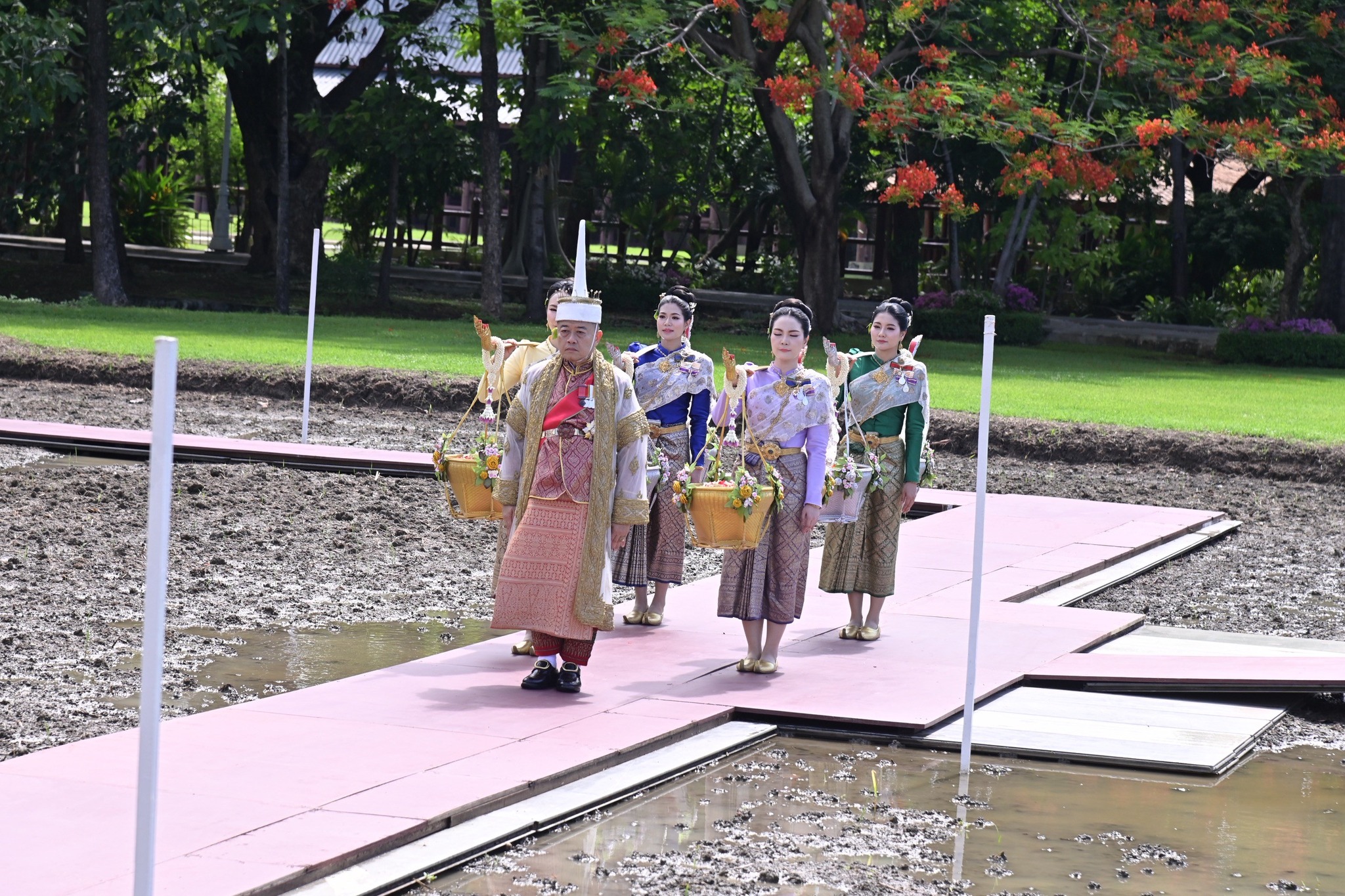 title - ปลัดเกษตรฯ ผู้ทำหน้าที่พระยาแรกนา พร้อมด้วยเทพีคู่หาบทอง และเทพีคู่หาบเงิน ประกอบพิธีหว่านเมล็ดพันธุ์ข้าวในแปลงนาทดลอง